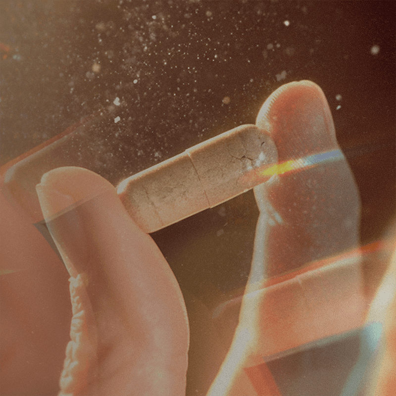 An image of two fingers holding up a multivitamin capsule